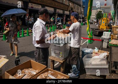 Vue horizontale d'un vendeur amusant de l'un des stands du marché extérieur de Tsukiji à Tokyo (Jogai-Shijo) essayant d'attirer des clients, Tsukiji, Tokyo Banque D'Images