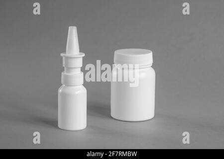 Bouteille de médecine vierge. Récipients médicaux en plastique blanc pour médicaments et vaporisateur nasal (décongestionnant) sur fond gris, maquette. Pharmacie Banque D'Images