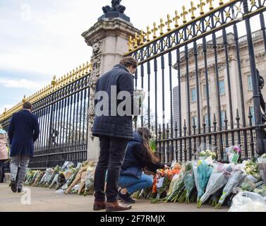 Londres, Royaume-Uni. 9 avril 2021. Un couple a posé des fleurs en hommage au prince Philip à l'extérieur de Buckingham Palace. Le duc d'Édimbourg est mort aujourd'hui, âgé de 99 ans. Credit: Vuk Valcic/Alamy Live News Banque D'Images