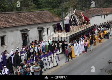 Des hommes bien habillés en costume et des femmes en tenue traditionnelle participent à la procession solennelle Semana Santa à Antigua, au Guatemala. Banque D'Images