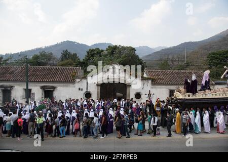 Des hommes bien habillés en costume et des femmes en tenue traditionnelle participent à la procession solennelle Semana Santa à Antigua, au Guatemala. Banque D'Images