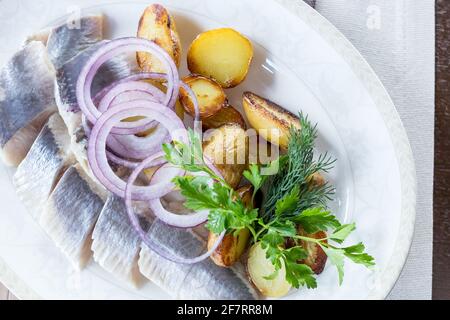Plateau de fruits de mer avec tranche de maquereau fumé, pommes de terre frites, tranches de filet de poisson, décoré d'oignons Banque D'Images