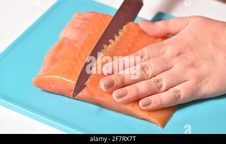 Le chef coupe le poisson rouge en fines tranches Banque D'Images