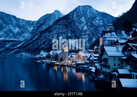 Hallstatt CityScape lors d'une soirée d'hiver froide couverte de neige Avec le lac Hallstaetter Voir et l'église illuminée la nuit Banque D'Images