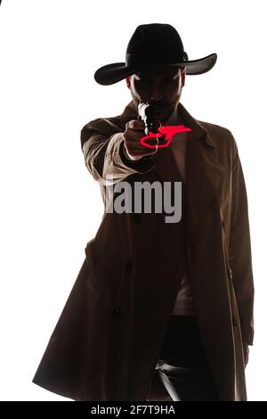 Sympa, un homme beau portant un élégant long manteau et un chapeau noir, pointant un pistolet Banque D'Images