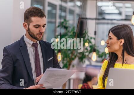 Le responsable explique à son employé comment terminer ses tâches. Collègues discutant d'un projet en se tenant dans un bureau. Banque D'Images