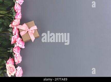 Jolies roses roses avec boîte-cadeau devant sur fond gris Pour le concept de fête des mères Banque D'Images