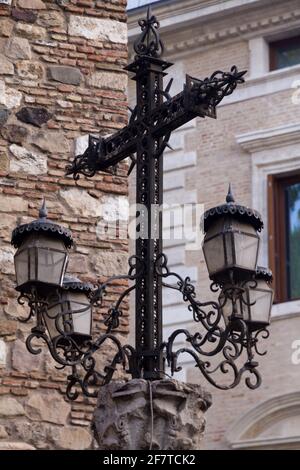 Détail d'une ancienne lampe en métal noir dans la forme d'une croix devant un mur de briques une journée ensoleillée Banque D'Images