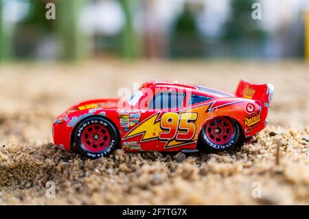 POZNAN, POLOGNE - 30 mars 2021 : voiture de sport miniature Red Lightning McQueen du film Disney Pixar Cars sur sable. Banque D'Images