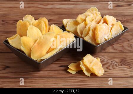 Morceaux séchés de mangue et de jackfruit sur une table en bois, placés sur des bols en céramique marron. Macro. Gros plan Banque D'Images