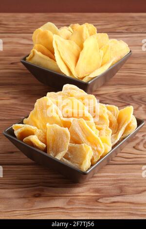 Morceaux séchés de mangue et de jackfruit sur une table en bois, placés sur des bols en céramique marron. Macro. Gros plan Banque D'Images