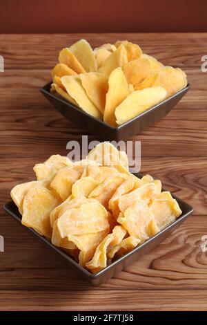 Morceaux séchés de mangue et de jackfruit sur une table en bois, placés sur des bols en céramique marron. Macro. Gros plan Banque D'Images