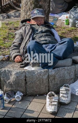 Homme japonais sans-abri dormant au soleil après avoir bu des canettes de bière, Ueno Park, Tokyo, Japon Banque D'Images