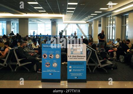 Un masque facial et un panneau de conseil de distance sociale à la porte 41 du terminal 4 de l'aéroport international de Los Angeles, le vendredi 9 avril 2021, à Los Angele Banque D'Images