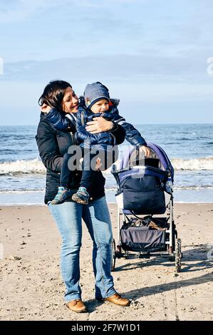 SARBINOWO, POLOGNE - 17 octobre 2017 : femme tenant un enfant à côté d'une poussette sur une plage Banque D'Images