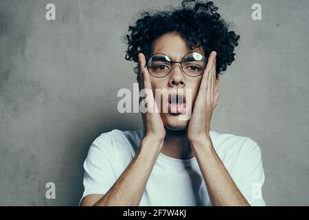 guy avec cheveux bouclés émotions verres mode studio gros plan Banque D'Images