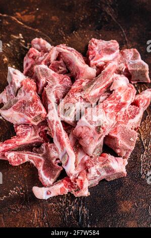 Viande crue sur l'os coupée en dés pour ragoût. Arrière-plan sombre. Vue de dessus Banque D'Images