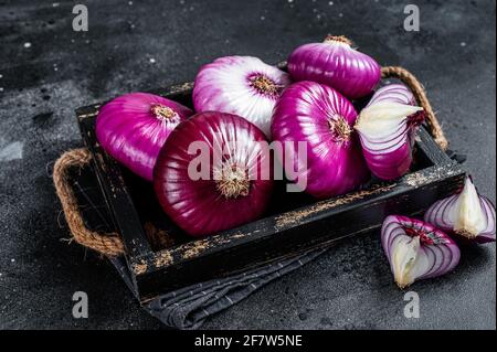 Oignon doux rouge plat dans un plateau en bois fond noir. Vue de dessus Banque D'Images