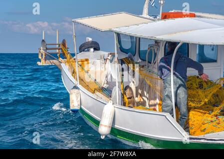 Les pêcheurs pêchent des poissons frais à l'aide de filets de pêche jaunes, sur un bateau de pêche, en Crète, en Grèce Banque D'Images