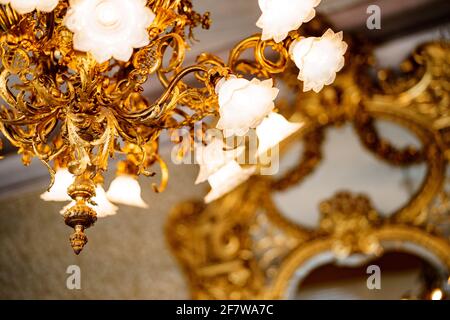 Grand lustre doré avec des tons floraux et des ampoules de style floristique. Gros plan sur les nuances et les détails floraux. Banque D'Images