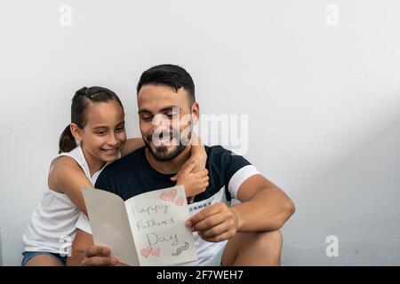 Homme adulte souriant lisant une carte postale que sa fille lui a donnée le jour du Père. Banque D'Images