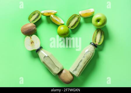 Coeur fait de bouteilles avec smoothie savoureux et fruits sur couleur de fond Banque D'Images