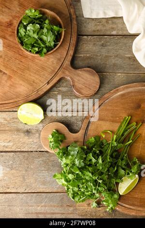 Planches avec cilantro frais et citron vert sur fond de bois Banque D'Images