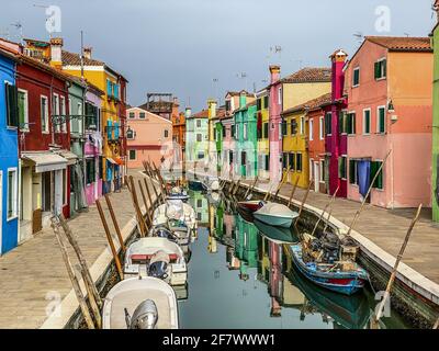 Bateaux et maisons colorées dans une rue de canal maisons sur l'île de Burano, Venise, une personne méconnaissable sur le fond. Banque D'Images