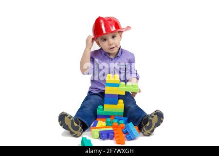 L'enfant s'assoit sur le sol avec des jouets répartis entre ses jambes isolé. Banque D'Images