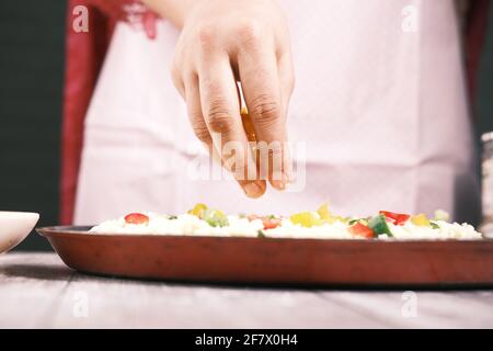 les jeunes femmes mettent du fromage sur la pizza Banque D'Images