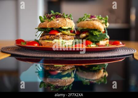 Burgers de pois chiches végétaliens avec des arugula, des concombres marinés, des tomates et de l'avocat sur la table Banque D'Images