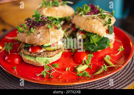 Burgers de pois chiches végétaliens avec des arugula, des concombres marinés, des tomates et de l'avocat sur la table Banque D'Images