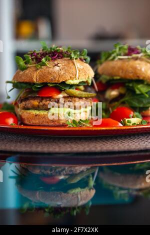 Burgers de pois chiches végétaliens avec des arugula, des concombres marinés, des tomates et de l'avocat sur la table Banque D'Images