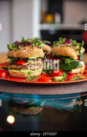 Burgers de pois chiches végétaliens avec des arugula, des concombres marinés, des tomates et de l'avocat sur la table Banque D'Images