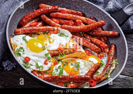 Longaniza con huevos, petit déjeuner de saucisses avec des œufs frits dans une poêle sur une table en bois, vue horizontale d'en haut, cuisine mexicaine Banque D'Images