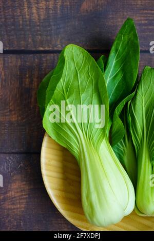 Une plaque de bambou avec le chou chinois brut pak choi. Banque D'Images