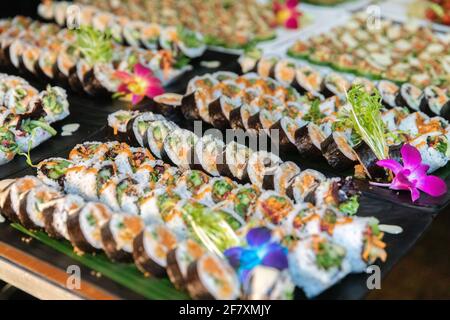 Présentation de beaucoup de tranches de sushis frais sur un assiette à un événement avec des fleurs Banque D'Images