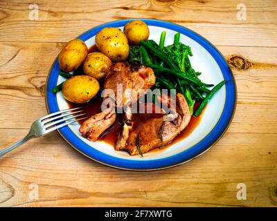 Déjeuner anglais dîner repas côtelettes d'agneau bouillies nouvelles pommes de terre vertes brocoli de haricots et sauce sur plaque blanche à bords bleus une table en bois Banque D'Images