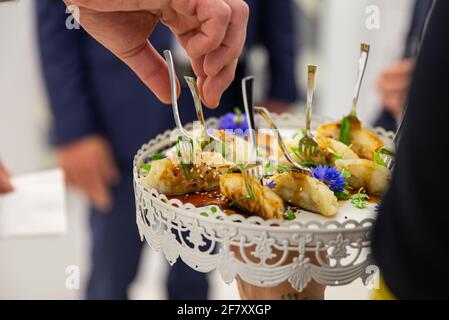 petites portions d'aliments sur une assiette avec une fourchette et une main pour atteindre un Banque D'Images