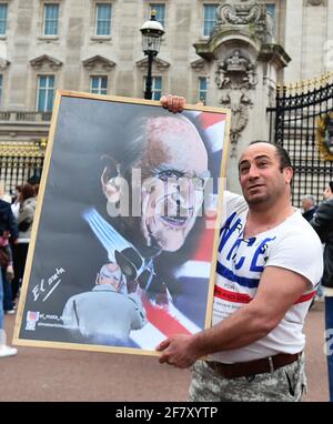 Un homme a une photo prise de lui-même tenant une œuvre du duc d'Édimbourg, devant le palais de Buckingham, à Londres, suite à l'annonce, le vendredi 9 avril, de la mort du duc d'Édimbourg à l'âge de 99 ans. Date de la photo: Samedi 10 avril 2021. Banque D'Images