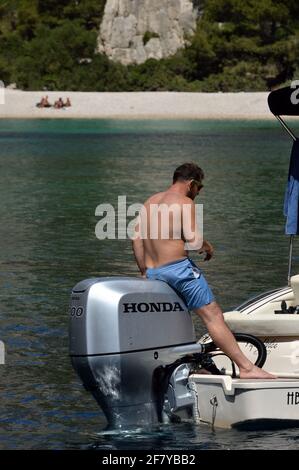 Hommes sur de petits bateaux amarrés au pied des falaises du parc national des Calanques près de Cassis, Provence, France, le 3 août 2020 Banque D'Images