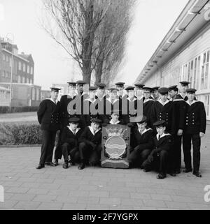 Photo de classe réalisée sur le site de la Marine Barracks Amsterdam (MKAD) lors des cours techniques de la Marine royale néerlandaise (Tokm). Une classe avec des conducteurs de la 3ème classe (Mach 3) pose avec les armoiries du Tokm. Banque D'Images