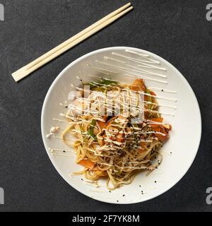 Chow mein nouilles et plat de légumes avec des baguettes en bois l'arrière-plan noir Banque D'Images