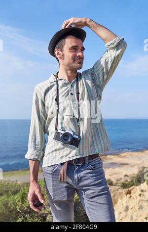 Un jeune touriste debout devant la caméra avec la mer en arrière-plan heureux d'être en mesure pour voyager et découvrir des lieux avec sa photographie Banque D'Images