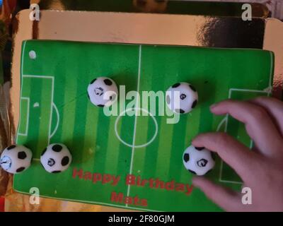 Gâteau d'anniversaire sportif amusant et charmant. Design avec le terrain de football. Chaussures, bâtiments, journée sportive. Gâteau, crème. Champ vert. Gâteau d'anniversaire pour un sport Banque D'Images