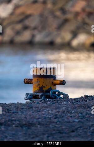 Helsinki / Finlande - 10 AVRIL 2021 : gros plan d'un bollard jaune avec une chaîne métallique attachée à celui-ci. Banque D'Images