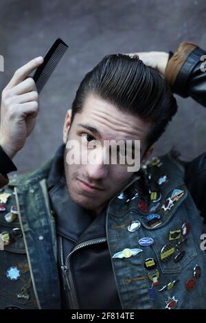 Rocker portant un Jean gilet avec des patches peignant son quiff en Londres, Angleterre . Veste personnalisée. Banque D'Images