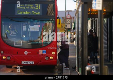 Vue latérale d'une jeune femme, portant un foulard hijab ou un couvre-tête entrant dans un bus à impériale à Londres, au Royaume-Uni. Banque D'Images