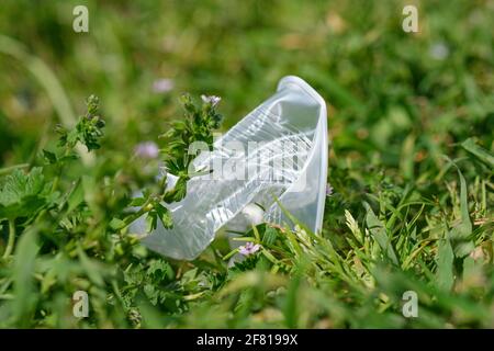 Gobelet en plastique jetable jeté sur le sol de prairie, pollution des déchets d'envinronment Banque D'Images