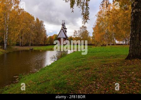 Ancienne église orthodoxe en bois se dresse sur la rive d'un lac forestier. Banque D'Images